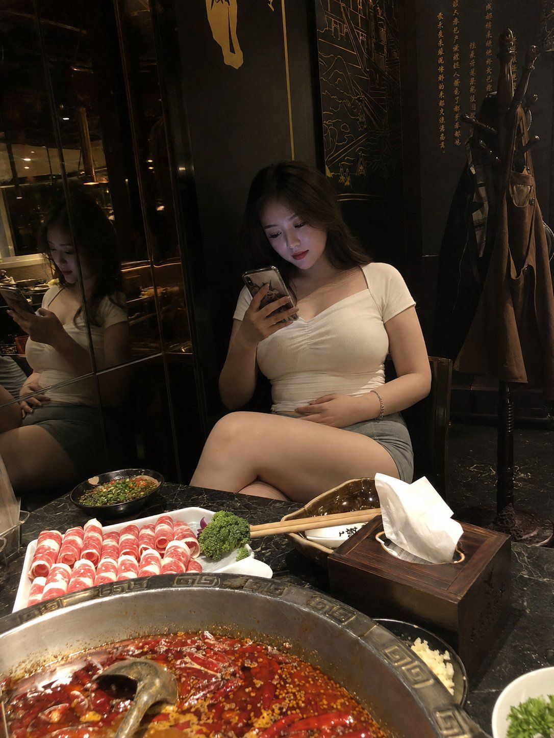 四川火锅店玩手机的中国年轻女子
